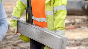 construction worker lifting concrete slab in hi-vis safety jacket