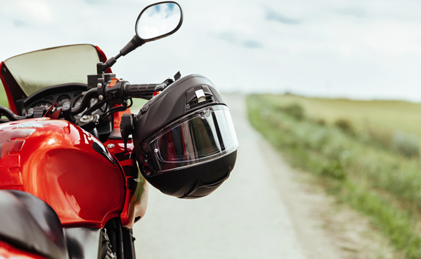 motorbike safety helmet hanging on bars of red bike