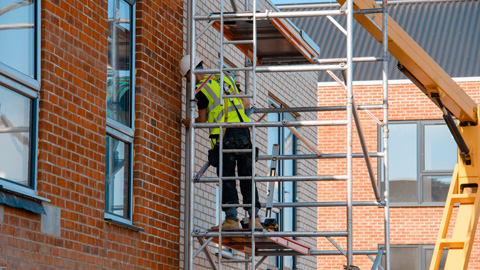 construction workers using mobile scaffold tower and safety harness to work at height