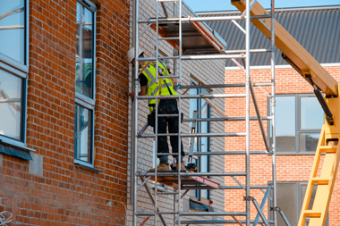 construction workers using mobile scaffold tower and safety harness to work at height